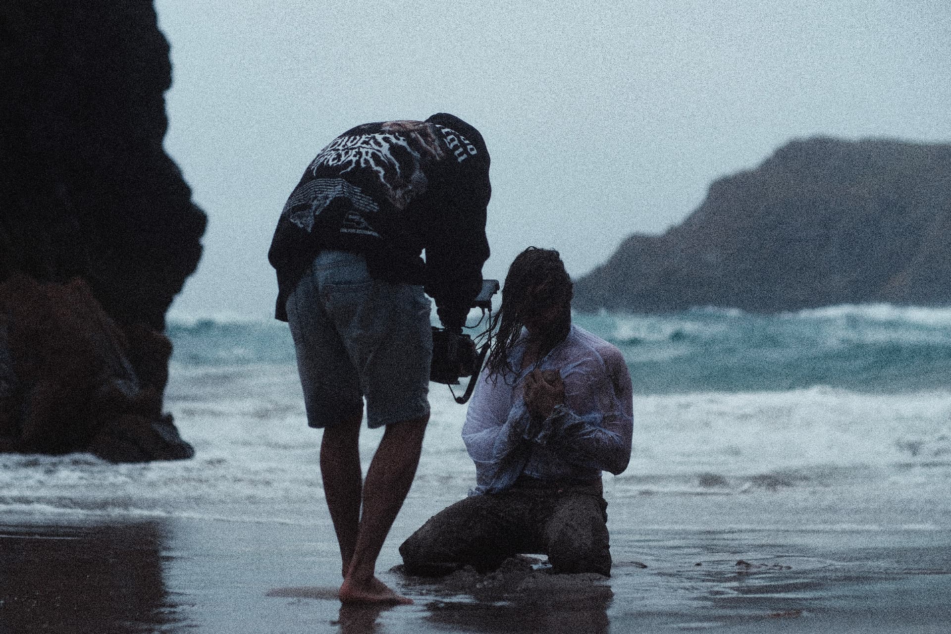 Filming a scene in the surf on a grey shoreline — TalesByTyler behind the scenes