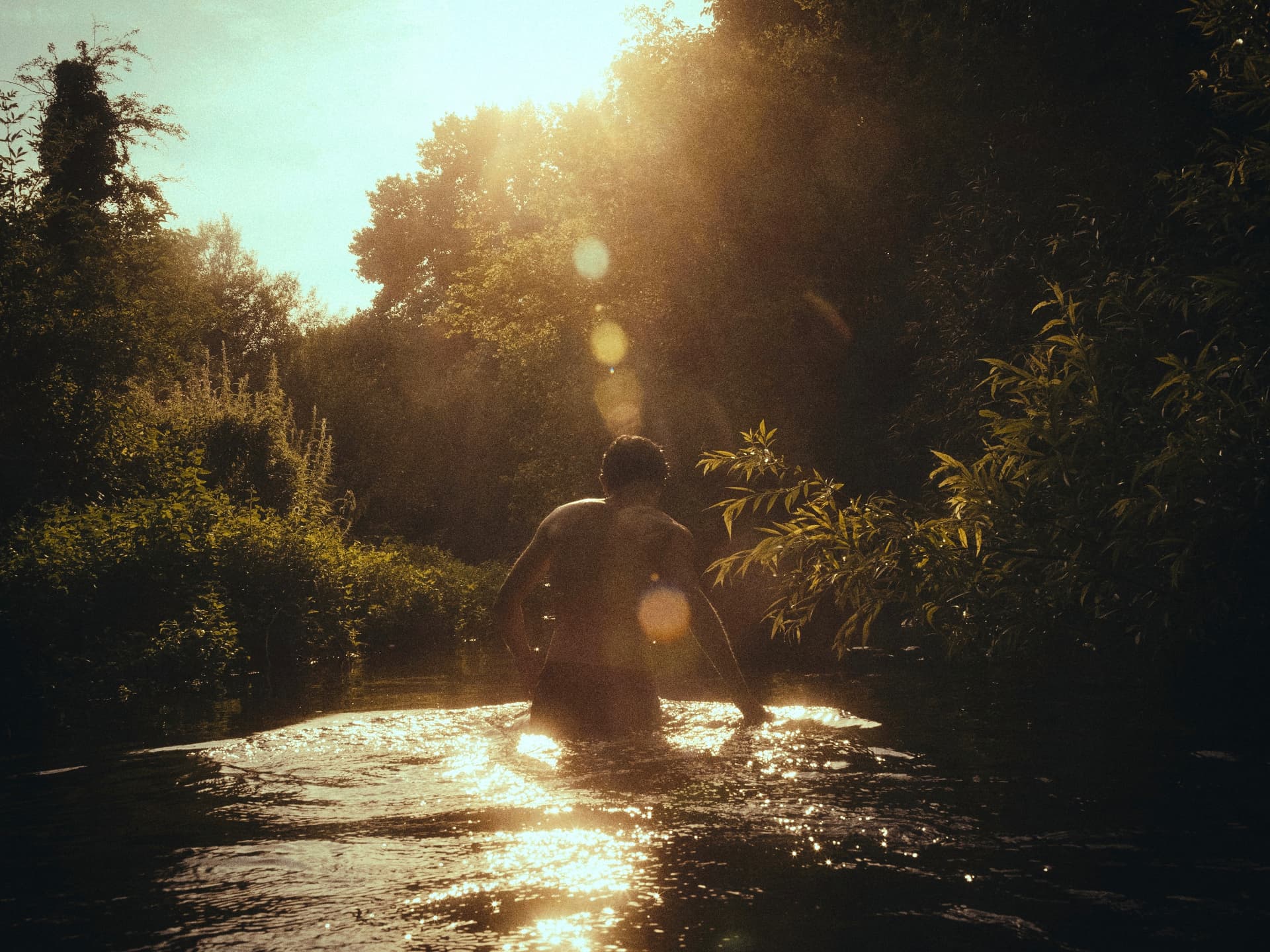 A figure wading through a sunlit river — a TalesByTyler film still
